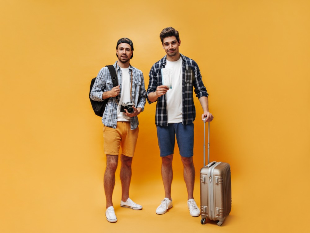 Fulllength Portrait Brunet Handsome Men Colorful Shorts Checkered Shirts White Tshirts Hold Suitcase Tickets Retro Camera Travelers Pose Orange Background