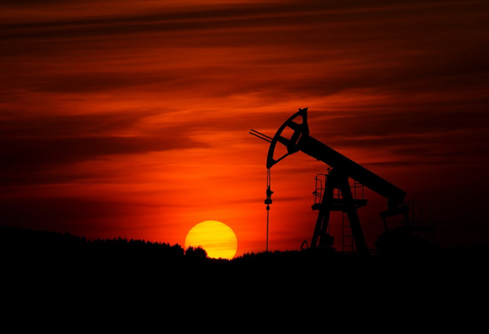 oil pump jack silhouette against red sunset