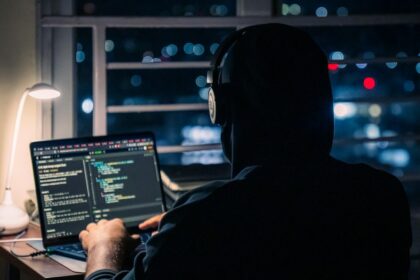 A person is coding on a laptop at night.